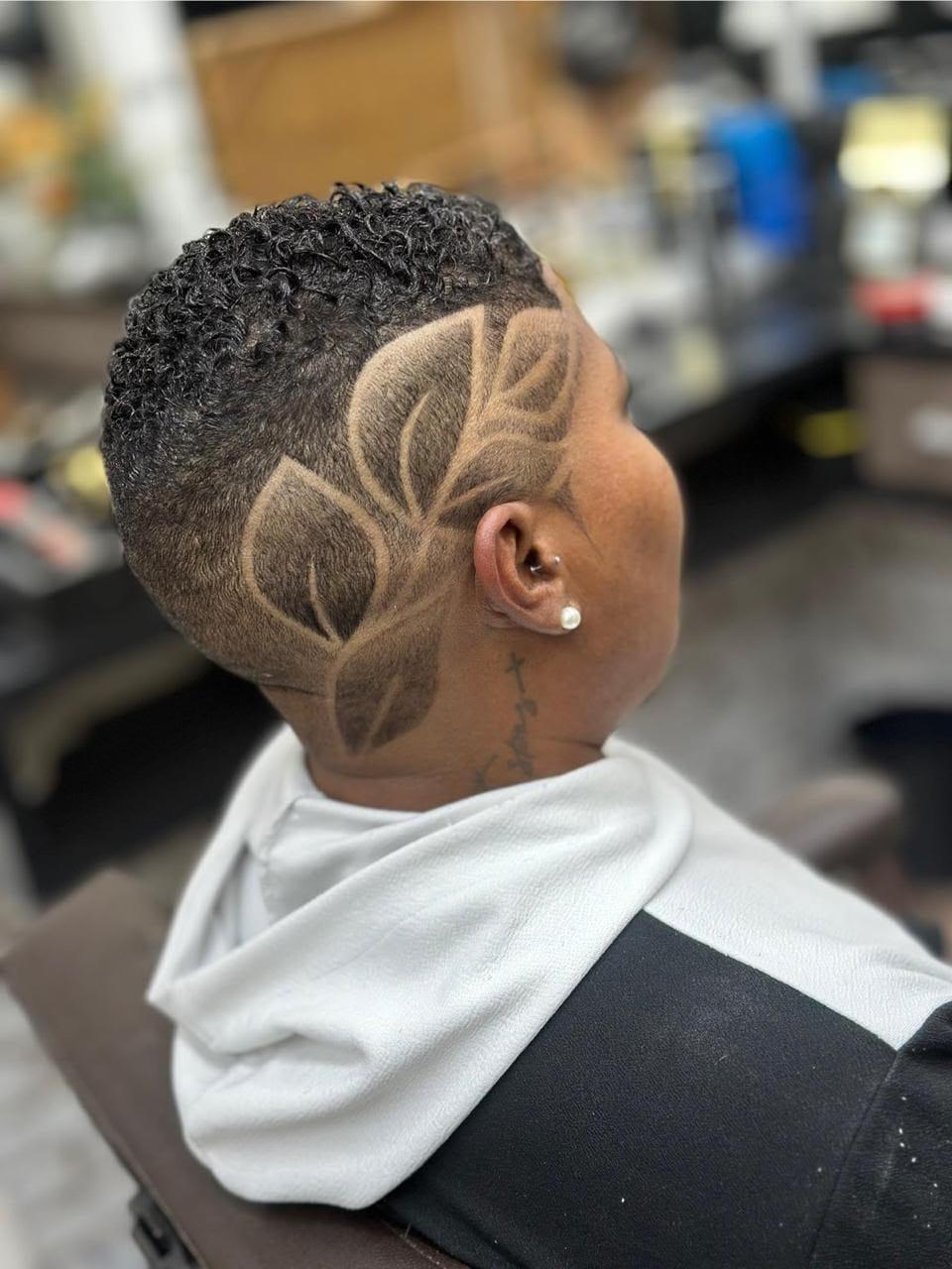 Corte cacheado com desenho de folhas raspado na lateral